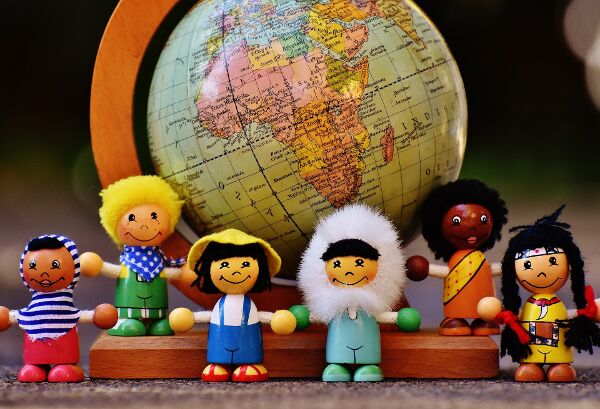 Dolls of multicultural children standing in front of globe